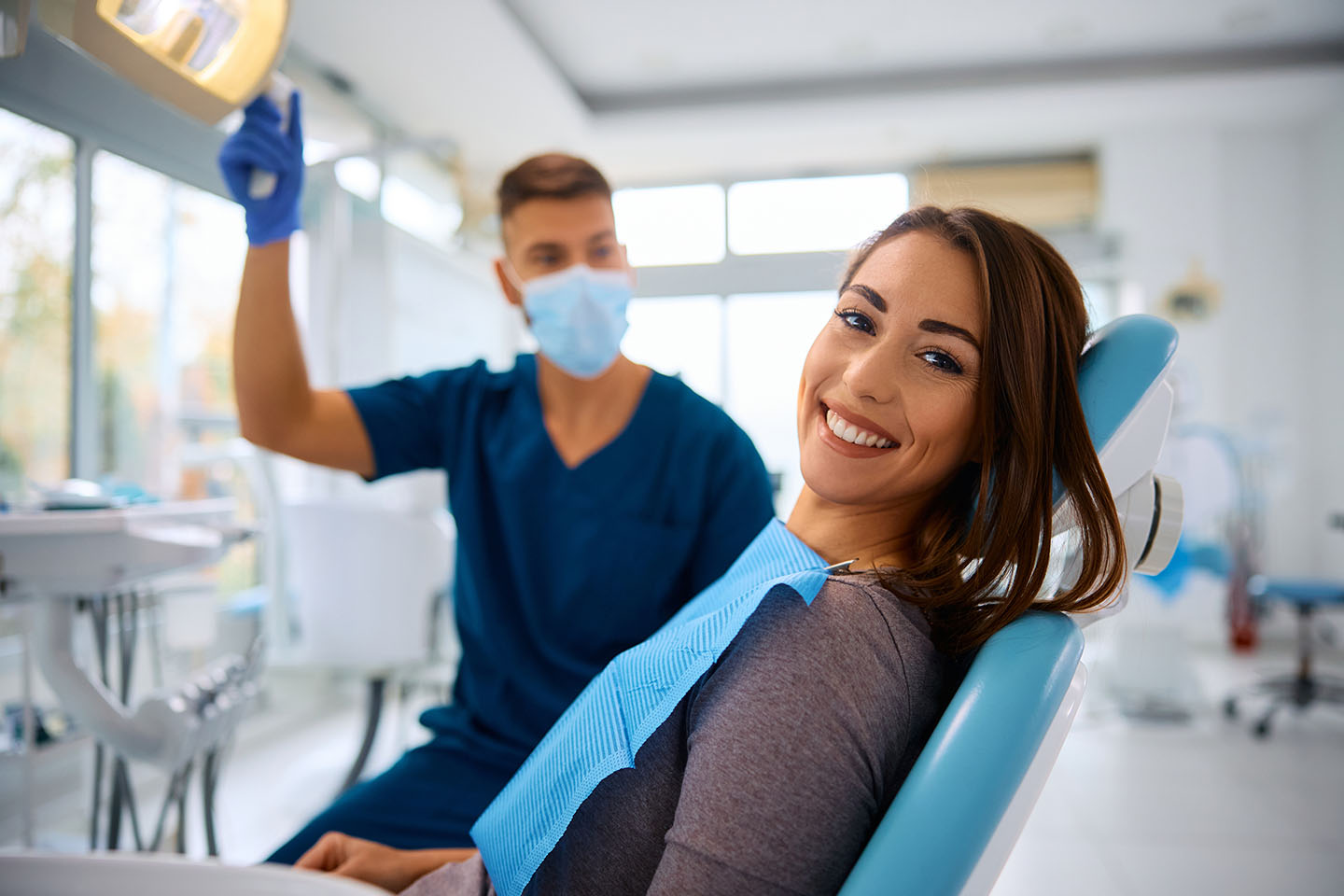 Young happy woman during teeth check-up at dental clinic looking at camera.